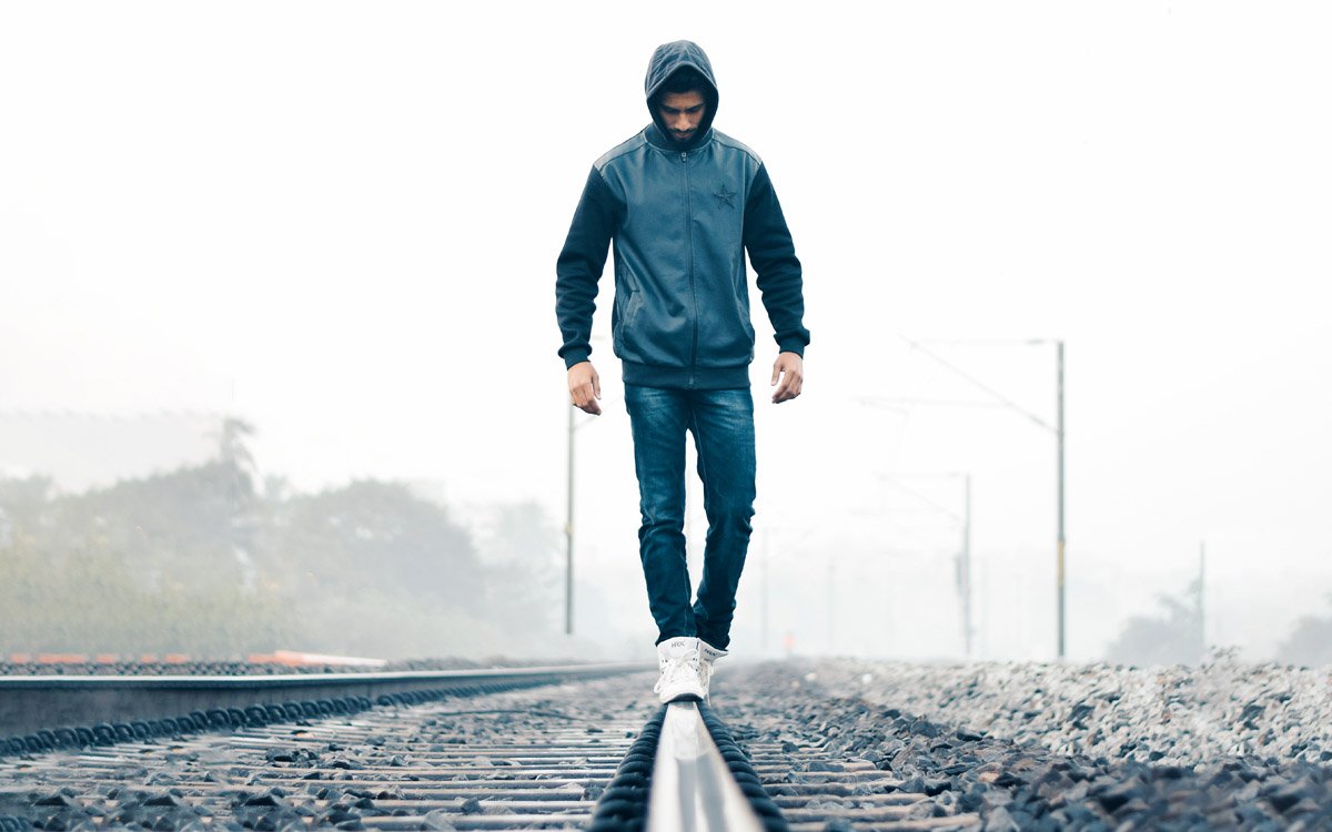 Man walking down a railroad track balancing